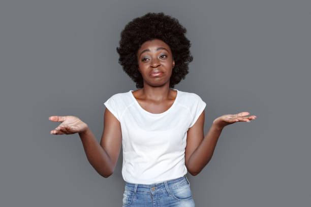 istock Young woman standing isolated on gray hands aside confused 1285857313