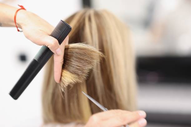 cabeleireiro segura tesoura e pente na mão e corta as pontas do cabelo - franja estilo de cabelo - fotografias e filmes do acervo