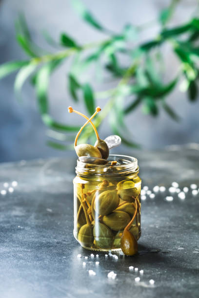 istock Marinated or pickled canned capers fruit close up in jar on gray kitchen table with copy space 1285857539