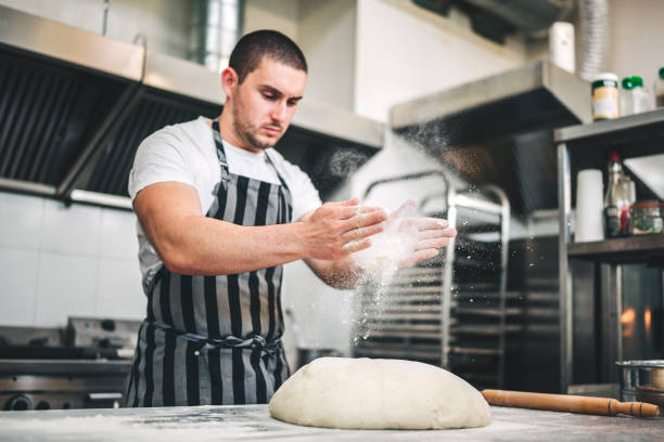 male chef preparing a pizza in the kitchen - chef baker bakery flour imagens e fotografias de stock