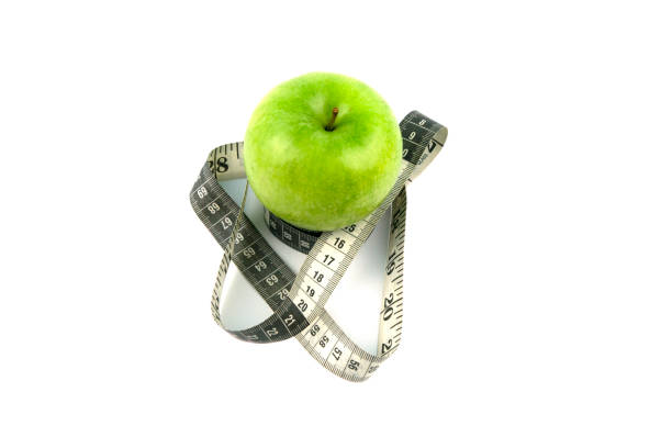 istock A green apple and a black and white measuring tape. 1285858979