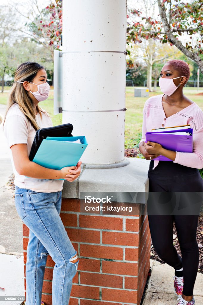Young adults talk between classes while wearing protective face masks Teenage high school students talk outdoors during a school break Protective Face Mask Stock Photo