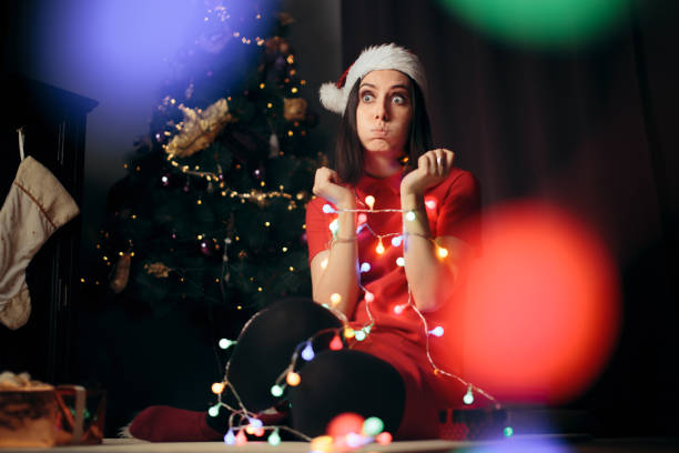 femme souligné emmêlé dans des lumières de fée sous l’arbre de noël - holiday emotional stress christmas santa claus photos et images de collection