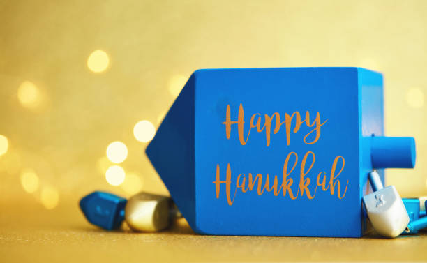 Hanukkah background with dreidel on gold and Happy Hanukkah message