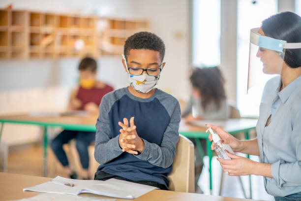istock Teacher sanitizes children's hands 1285871174