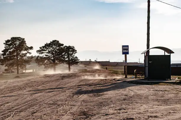 Photo of Unpaved Road full of dust and bus stop in the countryside