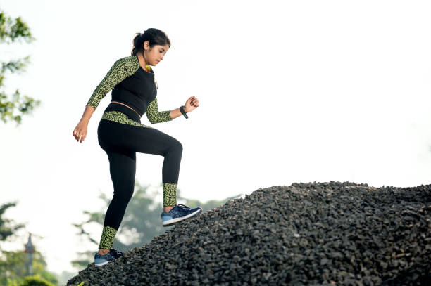 Young female athlete running on mountain or big rock.