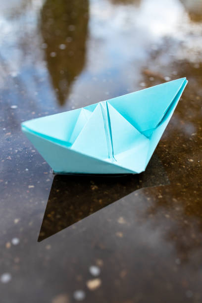 istock one blue paper ship floating on a water surface. outdoors. autumn season. greeting card with copy space. leadership conceptual. freedom concept 1285874493