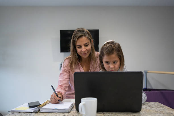 istock Girl studying at home using computer and her mother besides 1285874670