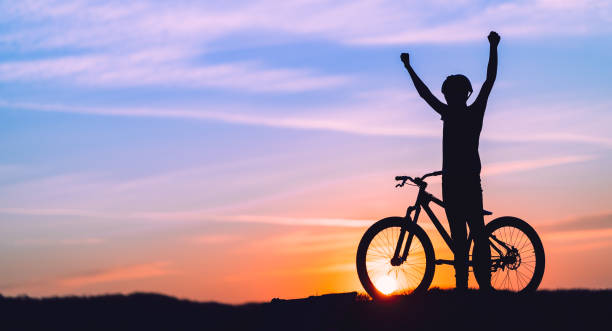 istock Silhouette of a mountain biker at sunset with arms raised 1285878159