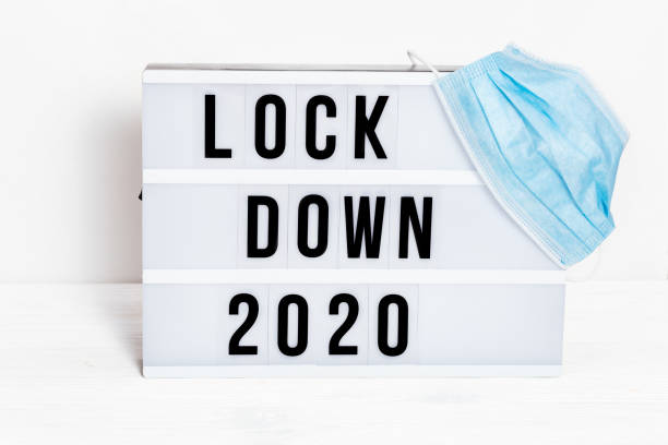 scatola luminosa con blocco dei messaggi 2020 e maschera protettiva chirurgica. la parola dell'anno 2020 è in lockdown. - housebound foto e immagini stock