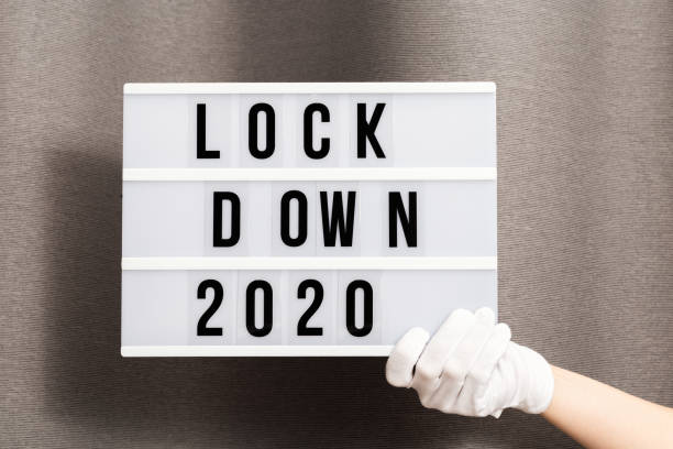 le mani in guanti bianchi tengono light box con blocco dei messaggi 2020. la parola dell'anno 2020 è in lockdown. - housebound foto e immagini stock