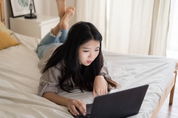 istock Asian Young women lying on the bed and using laptop.Work from home 1285880010
