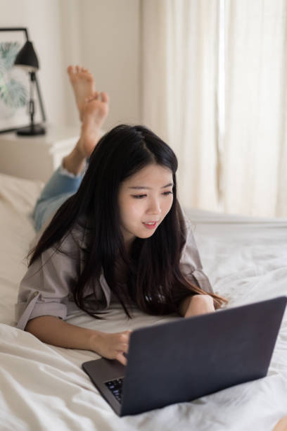 istock Asian Young women lying on the bed and using laptop.Work from home 1285880028