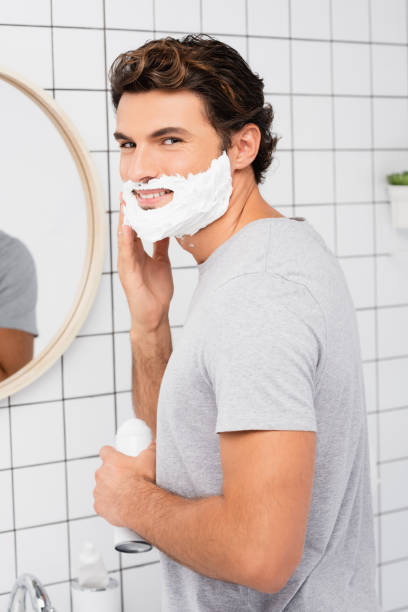 istock Smiling man applying shaving foam in bathroom 1285882130