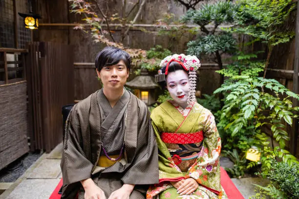 Young female tourist visiting Kyoto in Japan and experiencing Maiko (Geisha in training) makeover. 
Wearing traditional Japanese 'Maiko' style kimono with special white face makeup and walking around beautiful city of Kyoto.