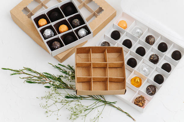 istock Fancy wrapped chocolate candies in sectioned boxes next to empty ones 1285886106