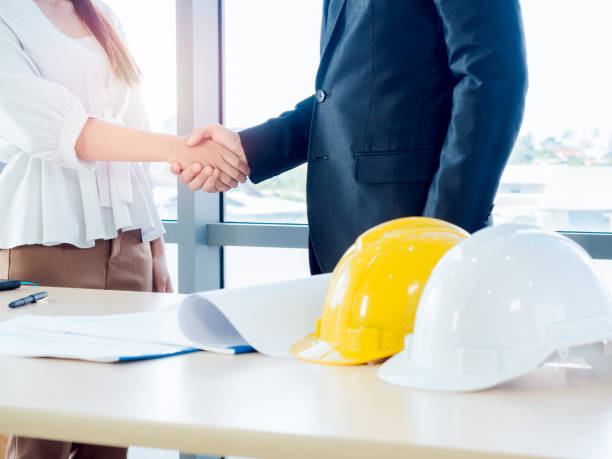 istock Asian male chief architect or engineer in suit and young female discuss on blueprint on desk. 1285888708