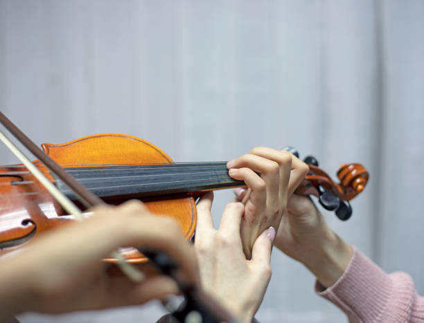 istock helping the teacher to keep his hand on the violin correctly, placing children's hands when playing the violin 1285893337