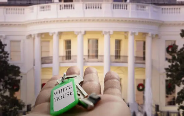 Illustration of the concept of presidential transition after elections before taking over the administration of federal government. Hand holding white and purposely blurred white house in background