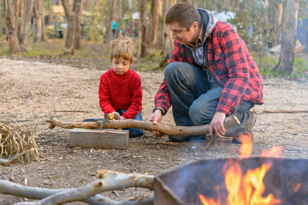 istock Father helping his son to cut a log for a camp fire 1285894221