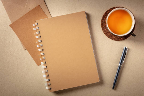 A notebook on a desk, shot from the top on a rustic background A notebook on a desk, shot from the top on a rustic background with a cup of tea and a pen bullet journal photos stock pictures, royalty-free photos & images
