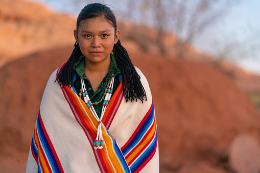 Navajo young girl portrait in front of a hogan