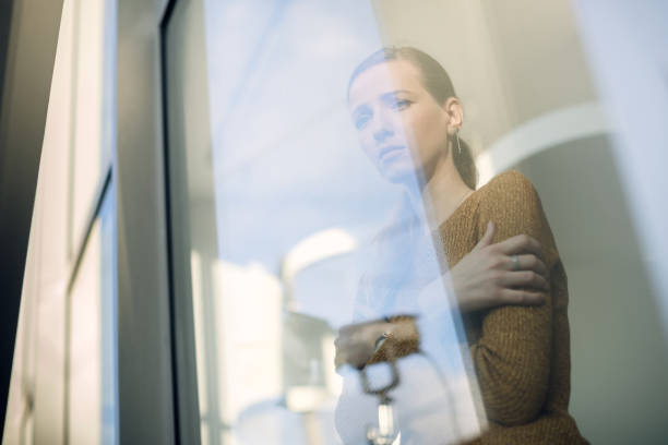 istock Below view of depressed woman looking through the window. 1285896506