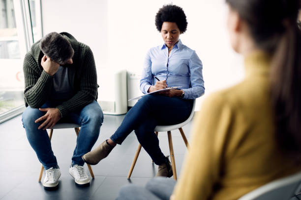 istock Black psychotherapist writing notes during group therapy at community center. 1285897303