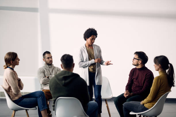 istock African American woman standing while talking during group therapy meeting. 1285897748