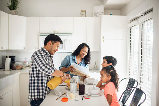 Hispanic family with two children eating breakfast in the kitchen