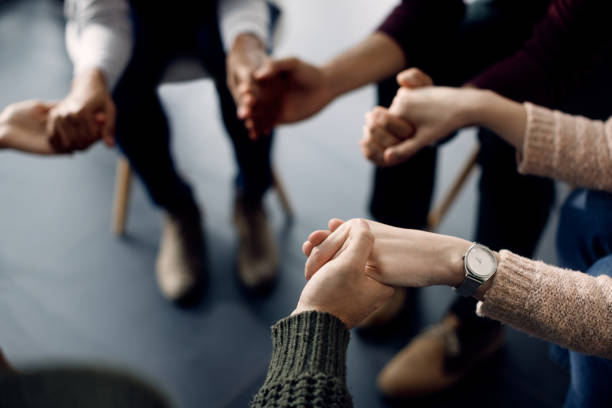 Close-up of attenders of group therapy holding hands during the meeting. Close-up of people holding hands while sitting in a circle during group therapy. group therapy photos stock pictures, royalty-free photos & images