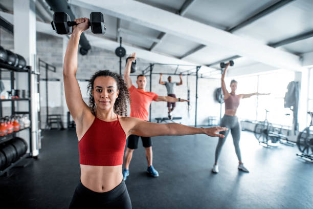 istock Hispanic Woman Exercising With Friends Using Dumbbells 1285901374