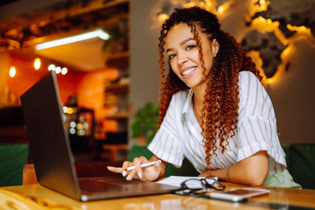 istock Young woman working online on laptop computer sitting in cafe. Freelancer working outside office. 1285904536