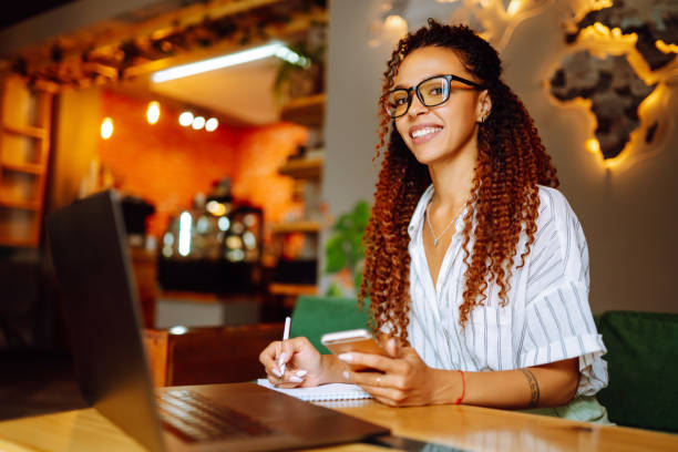 istock Young woman working online on laptop computer sitting in cafe. Freelancer working outside office. 1285904561