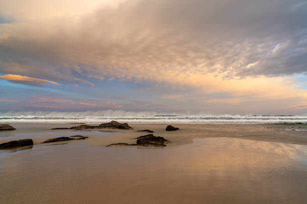 istock sunrise on a beautiful empty beach with waves crashing and rocks in the sand 1285905812