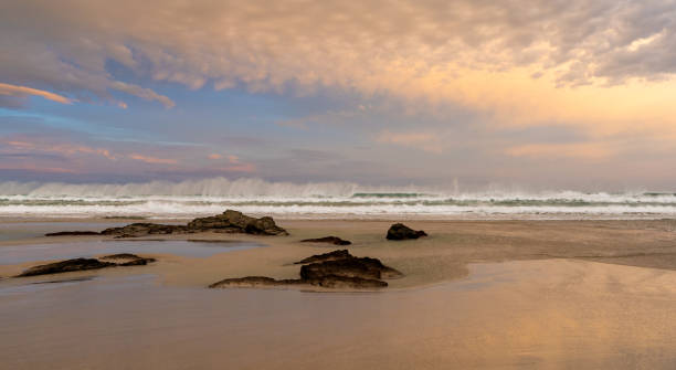 istock sunrise on a beautiful empty beach with waves crashing and rocks in the sand 1285909069