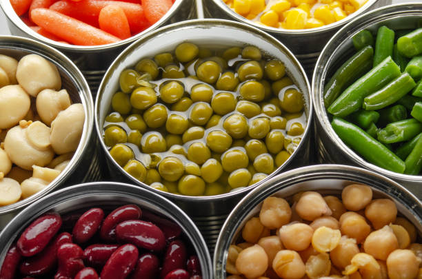 istock Canned vegetables in opened tin cans on kitchen table. Non-perishable long shelf life foods background 1285912158
