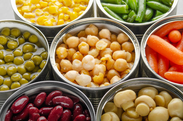 istock Canned vegetables in opened tin cans on kitchen table. Non-perishable long shelf life foods background 1285912188