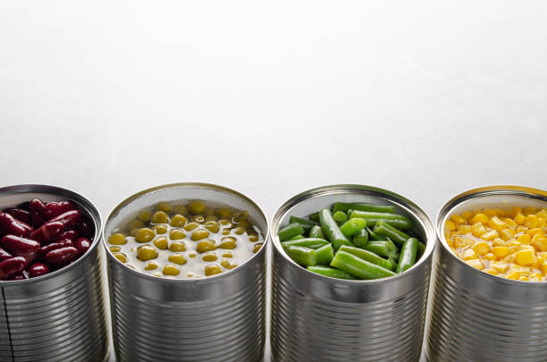 istock Canned kidney beans, green beans, peas and corn in opened tin cans on kitchen table. Non-perishable foods background 1285912244