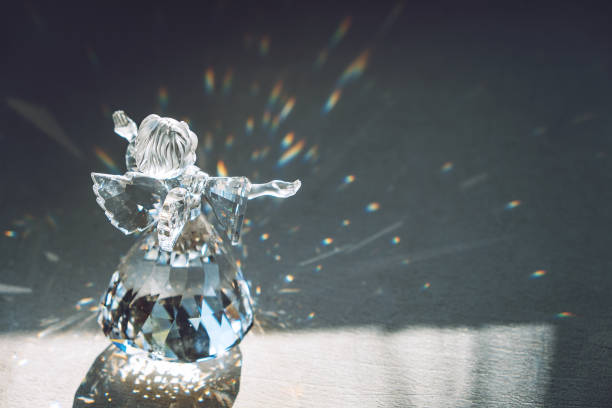 Crystal glass angel in the rays of the sun with reflecting, embossed sparkle. Faith, hope, mercy concept Crystal glass angel in the rays of the sun with reflecting, embossed sparkle. Faith, hope, mercy concept. prism photos stock pictures, royalty-free photos & images
