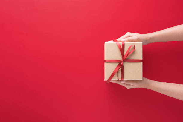 istock hand holding gift box with Merry Christmas and Happy New Year 1285913562