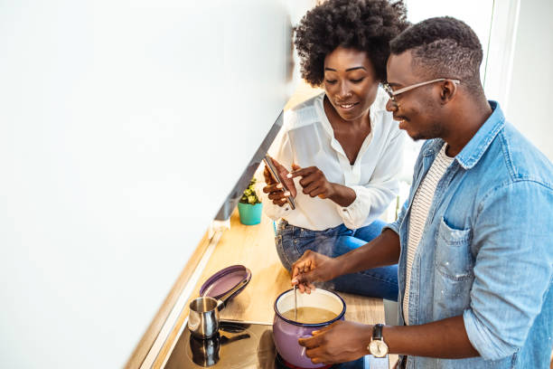 istock Beautiful young couple is using a smartphone and smiling while cooking in kitchen at home. 1285914828