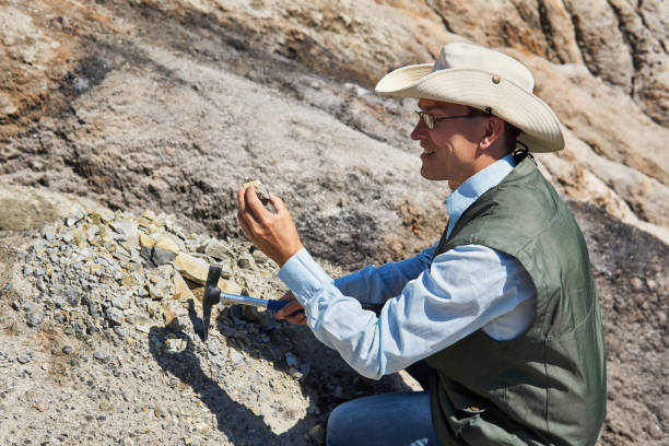 man geologist examines a rock sample in a desert area
