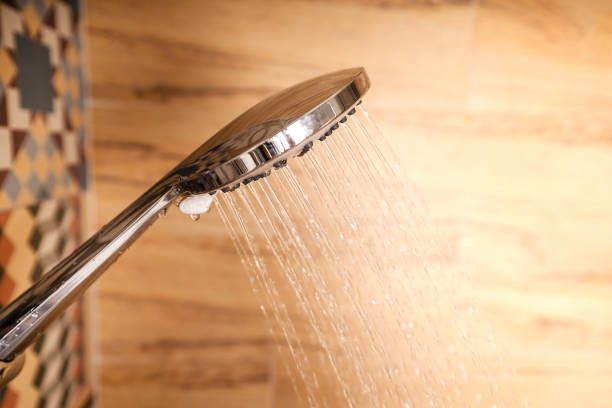istock Man's hand checking the water temperature in the shower using a hand-held shower wall in a bathroom with beautiful modern ceramic tiles. 1285916712