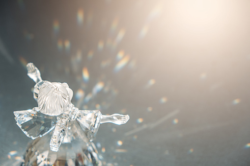 Crystal glass angel in the rays of the sun with reflecting, embossed sparkle. Faith, hope, mercy concept.