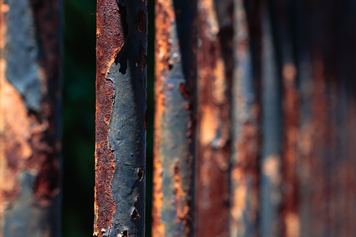 Part of an old rusty painted metal fence, with cracked and peeling paint.