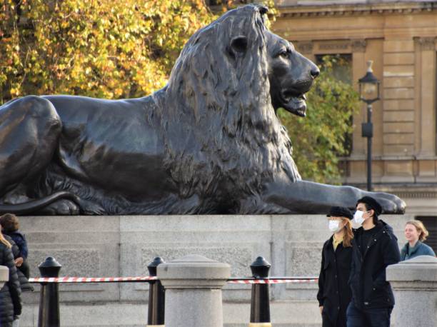 menschen mit gesichtsmasken am trafalgar square, london während der nationalen sperrung - city of westminster big ben london england whitehall street stock-fotos und bilder