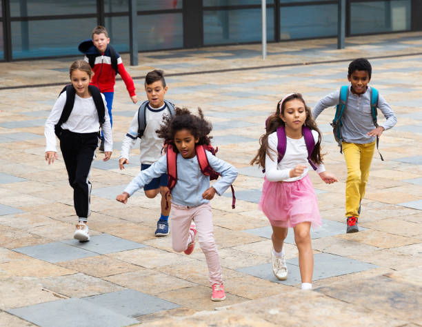 istock Group of cheerful tweenagers running in school yard after lessons 1285920333
