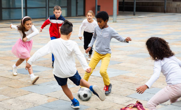 istock Cheerful tween schoolchildren playing with ball near school 1285920353